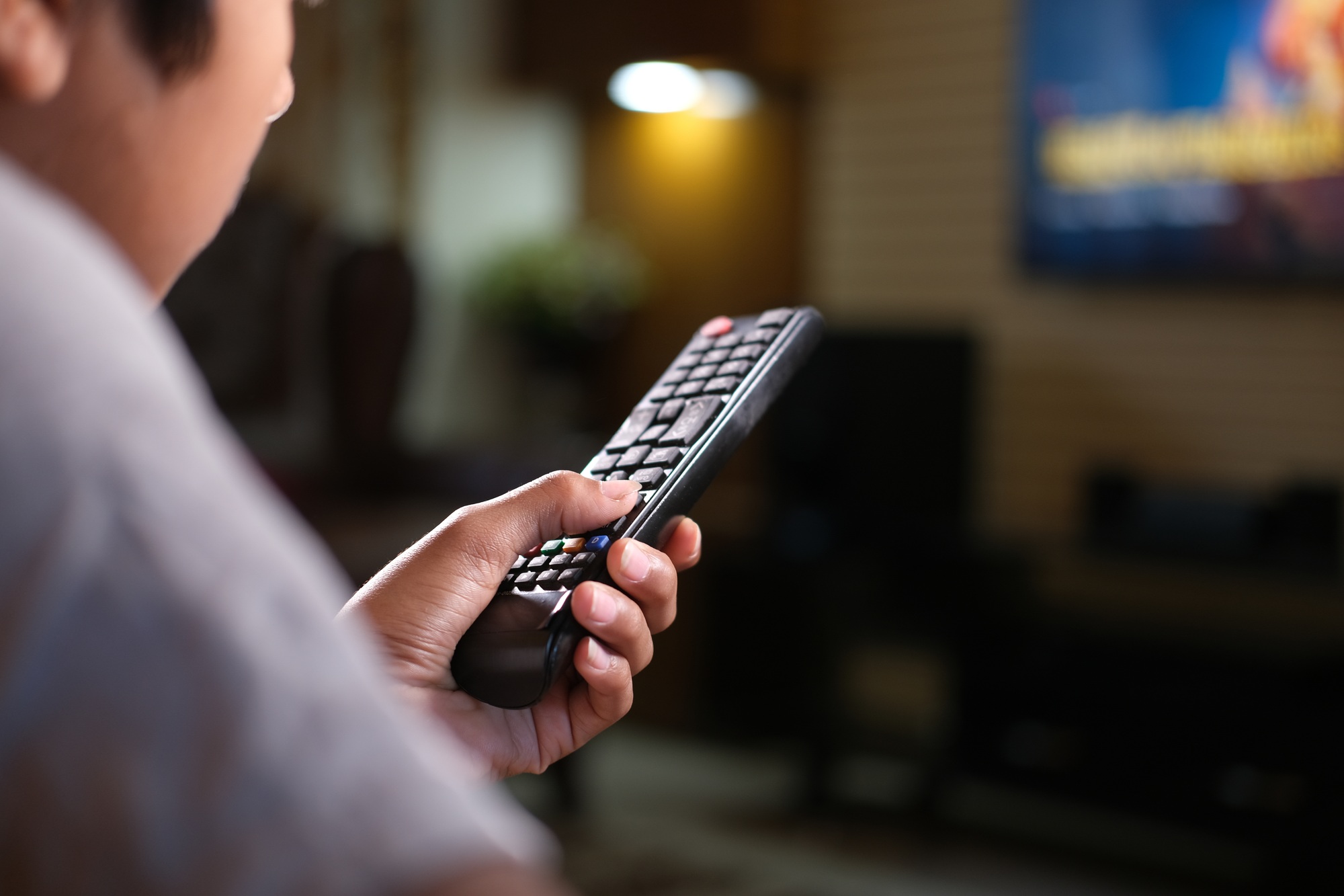 A person pointing a TV remote at a television