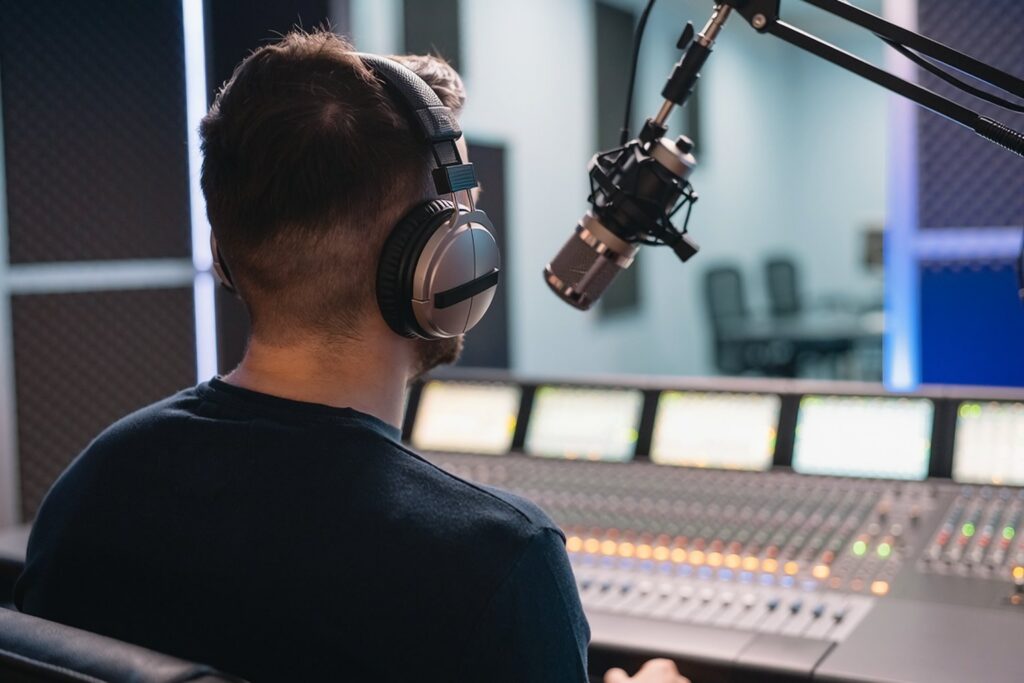 Radio host seen from behind at a broadcast microphone